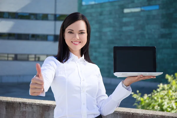 Beautiful business woman showing laptop with blank screen and th — Stock Photo, Image