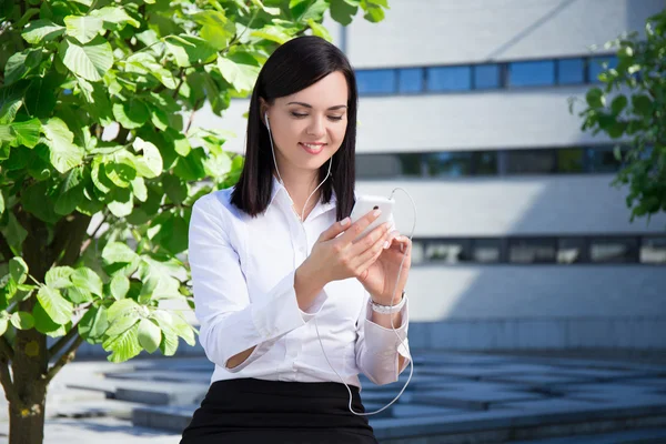 Entreprise jeune femme écoute la musique avec smartphone par ville — Photo