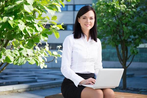 Business woman using laptop in city park — Stock fotografie
