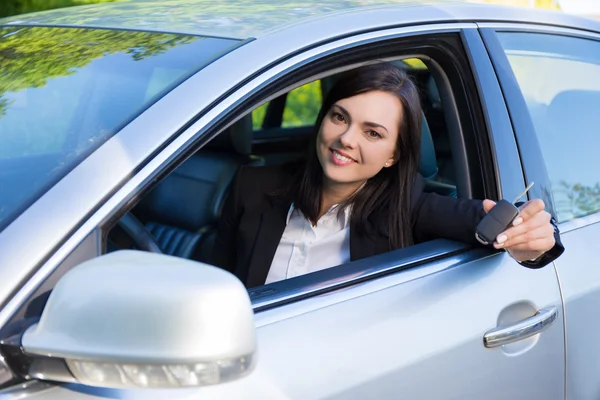 Бізнес-леді, що показує нові ключі від машини та автомобіль — стокове фото