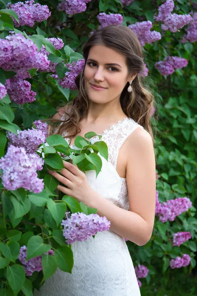 Retrato de la hermosa novia posando cerca árbol de flor lila — Foto de Stock