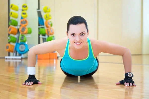 Mulher bonita fazendo push-up exercício no ginásio — Fotografia de Stock