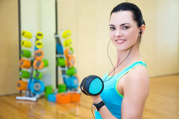 Beautiful sporty woman working out and listening music in gym — Stock Photo, Image