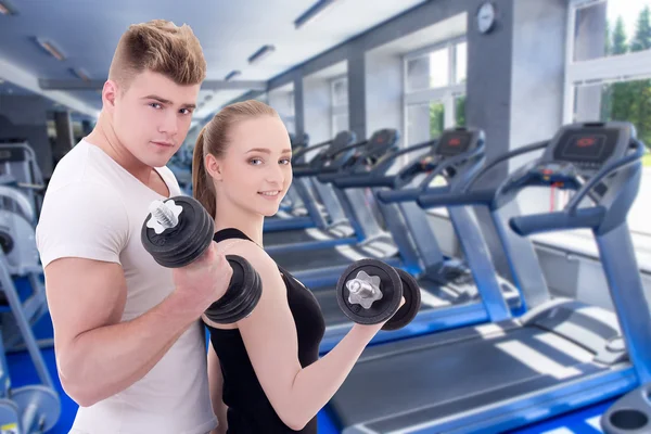 Retrato de homem e mulher no sportswear com halteres no ginásio — Fotografia de Stock