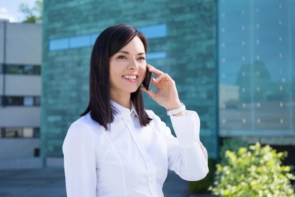 Young business woman talking on smartphone at street — Stock Photo, Image