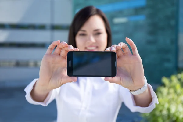 Young beautiful business woman showing smartphone with blank scr — Stock Photo, Image