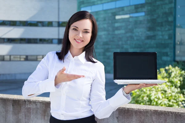 Beautiful business woman showing laptop with blank screen — Stock Photo, Image