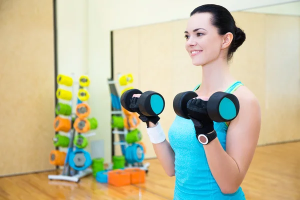 Happy sporty woman exercising with dumbbell in gym — Stock Photo, Image