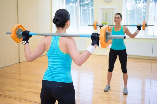 Conceito de musculação - vista traseira da jovem mulher exercitando com — Fotografia de Stock