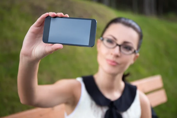 Krásná žena zobrazeno chytrý telefon s prázdnou obrazovkou — Stock fotografie