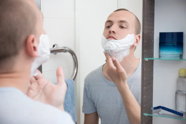 Man använda raklödder på hans ansikte i badrum — Stockfoto