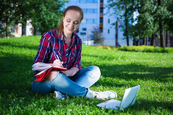 Teenage girl writing diary in park — Stok Foto