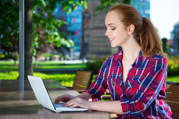 Tonårig flicka sitter med laptop i park — Stockfoto