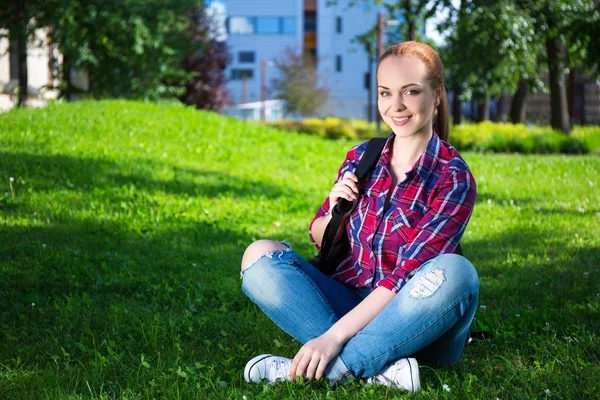 Teenage student girl with backpack sitting in park — Stock Photo, Image
