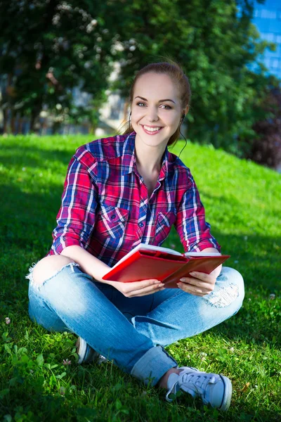 Teenage girl reading book in park — Stock Photo, Image