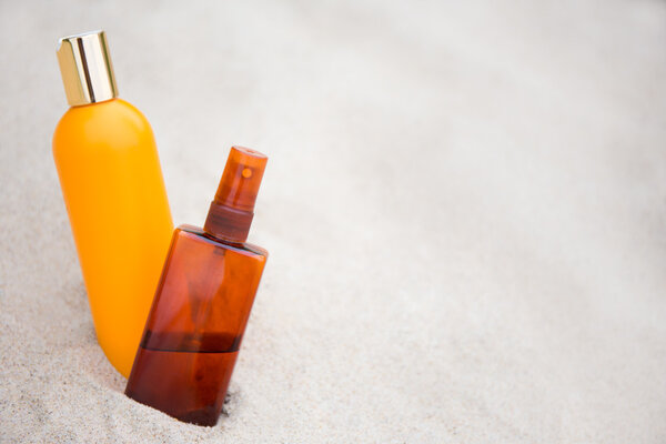 skin care concept -suntan lotion bottles in sand