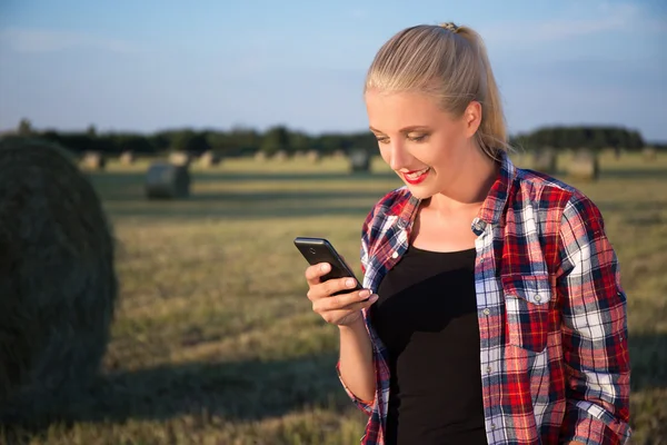 Gyönyörű szőke nő mozgatható telefon-ban mező a Szénaboglyák — Stock Fotó
