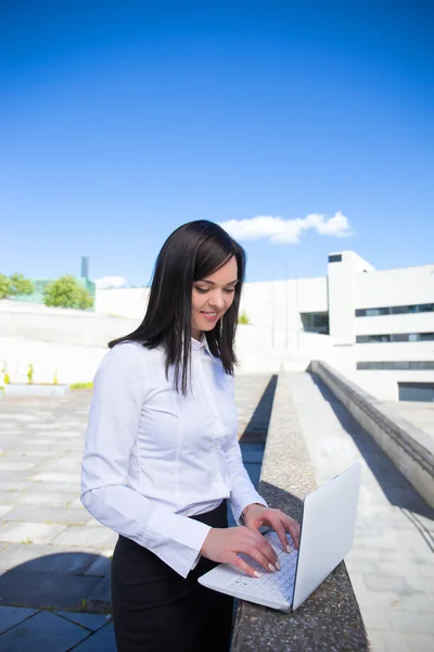 Business woman working on laptop outside office — Stock Photo, Image