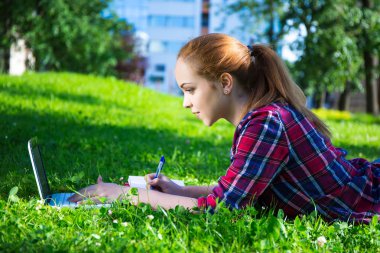 Genç öğrenci ya da dizüstü bilgisayar ile parkta yalan okul kız