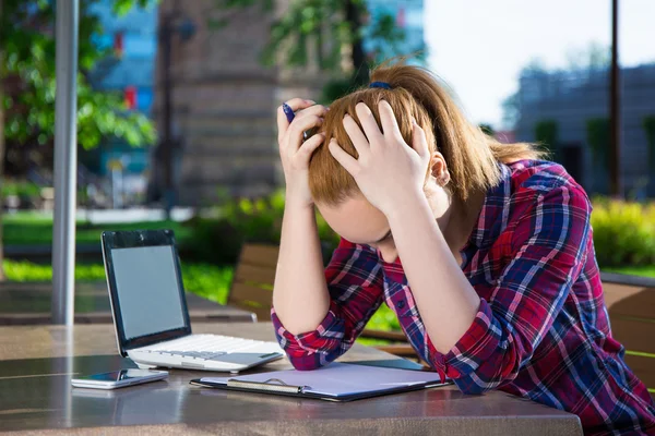 Verveeld tienermeisje werken met laptop in park — Stockfoto