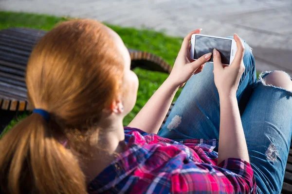 Dospívající dívka pomocí smartphonu v parku — Stock fotografie