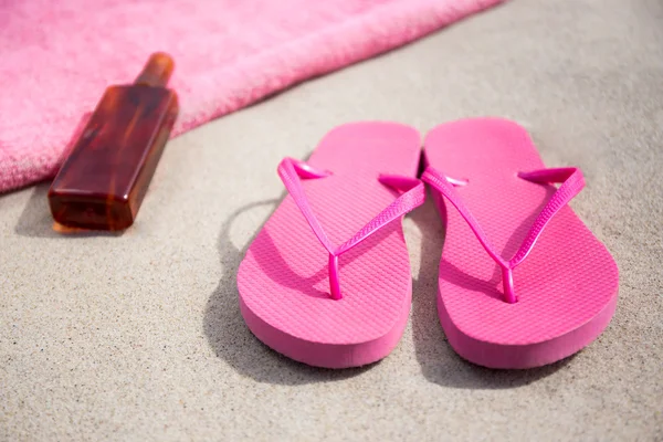 Summer concept - flip flops, towel and suntan lotion bottle on s — Stock Photo, Image