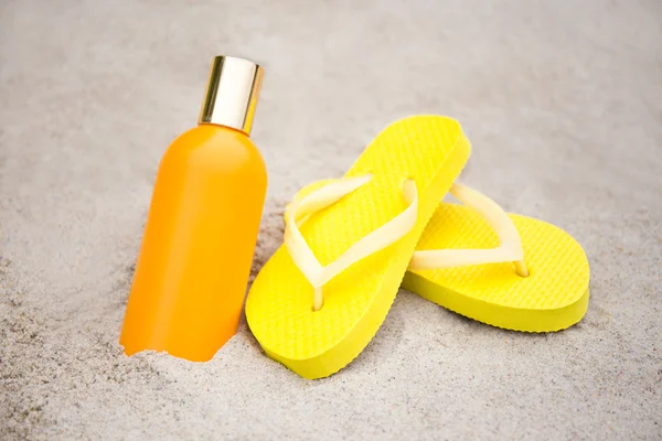 Estate e cura della pelle concetto - pantofole e bottiglia di lozione di suntan — Foto Stock