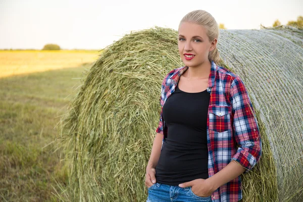 Gyönyörű szőke nő a Szénaboglyák mezőbe — Stock Fotó