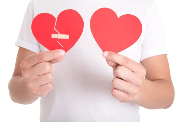 Homem segurando um coração partido com gesso e coração de papel normal — Fotografia de Stock