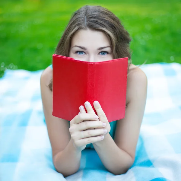 Portré, fiatal nő bujkál az arca mögött könyv közelről — Stock Fotó