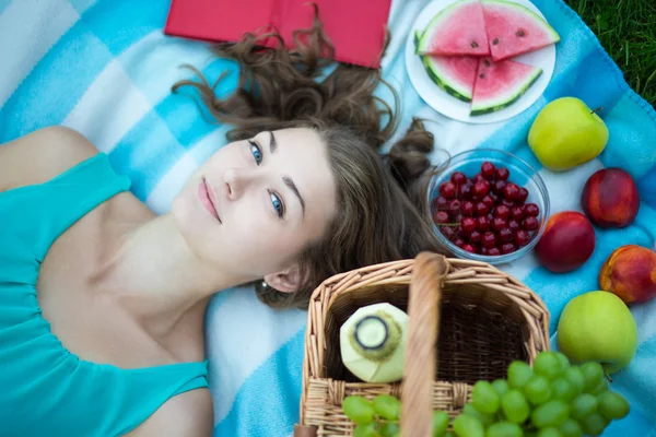 Vue de belle jeune femme avec panier pique-nique, fruits de dessus et — Photo