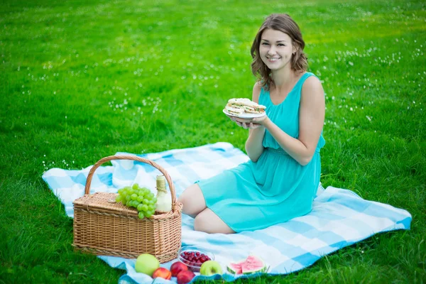 Jovem mulher bonita com a cesta de piquenique, frutas e sanduíches — Fotografia de Stock