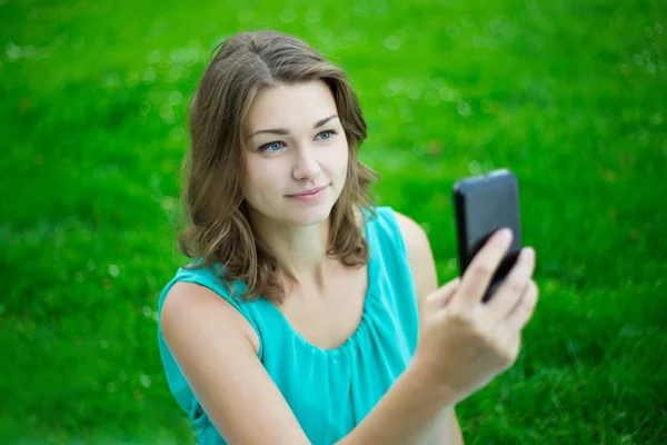 Young beautiful woman using smart phone in park — Stock Photo, Image
