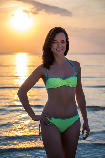 Hermosa mujer en bikini en la playa al atardecer — Foto de Stock
