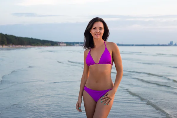 Slanke vrouw in bikini poseren over zee achtergrond — Stockfoto