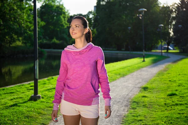 Donna sottile felice in abiti sportivi a piedi nel parco — Foto Stock