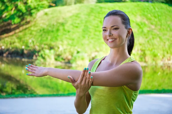 Femme souriante, faire des exercices d'étirement dans le parc — Photo