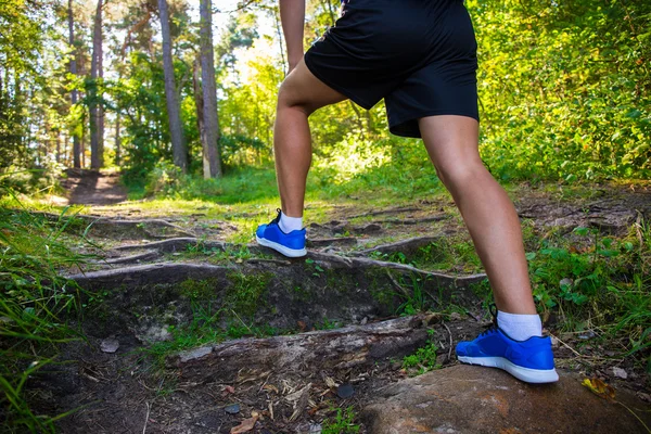 Koncepcja piesze wycieczki - bliska mężczyzna nogi w buty sportowe w lesie — Zdjęcie stockowe