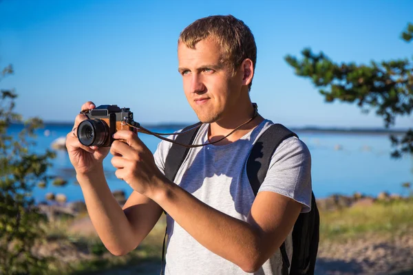 Mężczyzna z plecakiem i kamerą na plaży — Zdjęcie stockowe