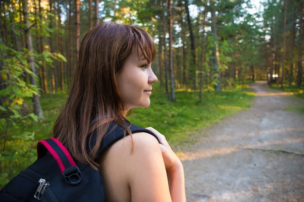 Resa koncept - kvinna med ryggsäck vandring i skogen — Stockfoto