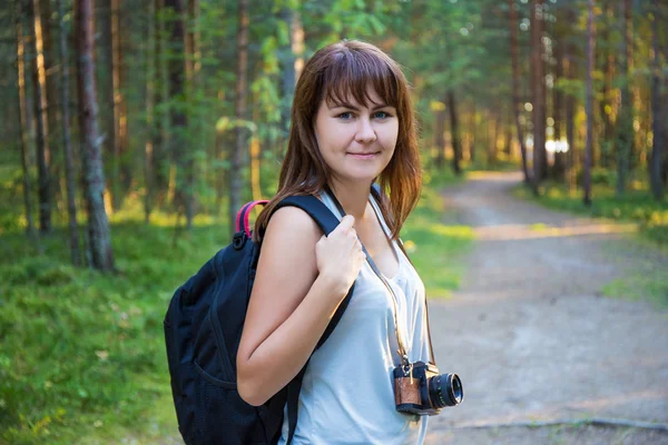 Ung kvinna med ryggsäck vandring i skogen — Stockfoto