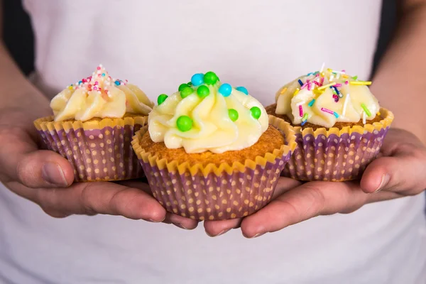 Cupcakes coloridos doces com creme de manteiga em mãos femininas — Fotografia de Stock