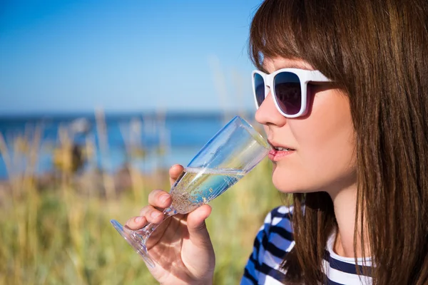 Retrato de hermosa mujer bebiendo champán en la playa — Foto de Stock
