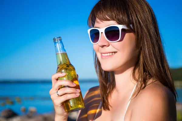 Mulher bonita feliz com cerveja posando na praia — Fotografia de Stock