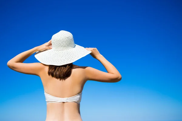 Back view of slim woman in bikini and hat over blue sky backgrou — Stock Photo, Image