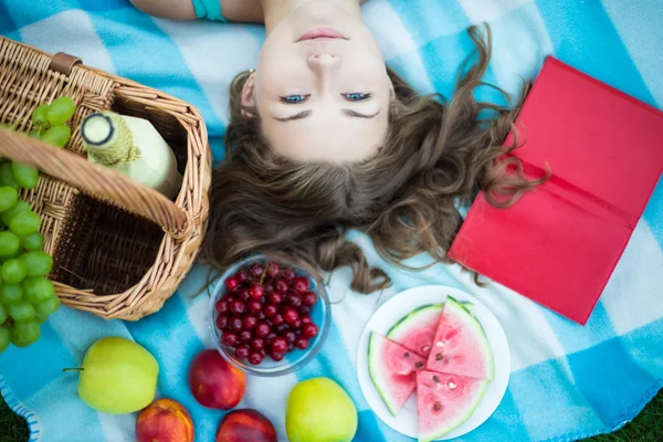 Top view of beautiful woman with picnic basket, fruits and book — Stock Photo, Image