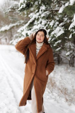 Ormanda kahverengi ceketli güzel bir kadın.