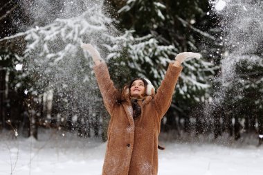 Mutlu kadın kış ormanına kar atıyor.