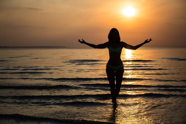 Sylwetka szczęśliwy kobiety w bikini na plaży o zachodzie słońca — Zdjęcie stockowe