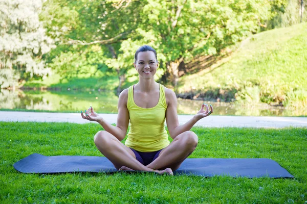 Parkta yoga egzersizi yapan genç bir kadın. — Stok fotoğraf